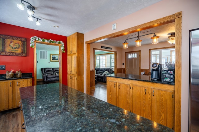 kitchen featuring dark wood finished floors, brown cabinets, hanging light fixtures, and a textured ceiling