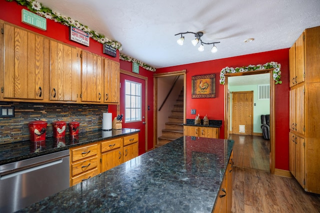 kitchen featuring visible vents, decorative backsplash, stainless steel dishwasher, brown cabinetry, and wood finished floors