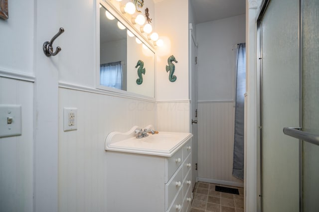 full bath featuring a shower, wainscoting, vanity, and tile patterned floors