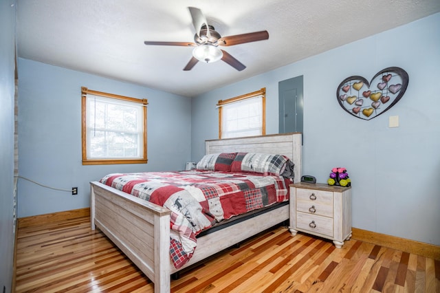 bedroom featuring light wood finished floors, multiple windows, and baseboards