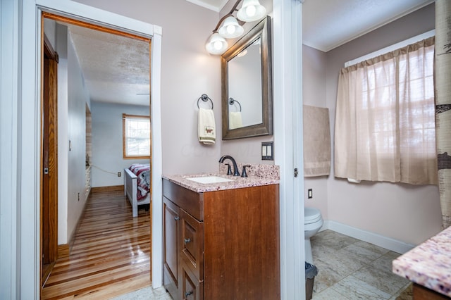 bathroom with baseboards, toilet, vanity, and ensuite bath