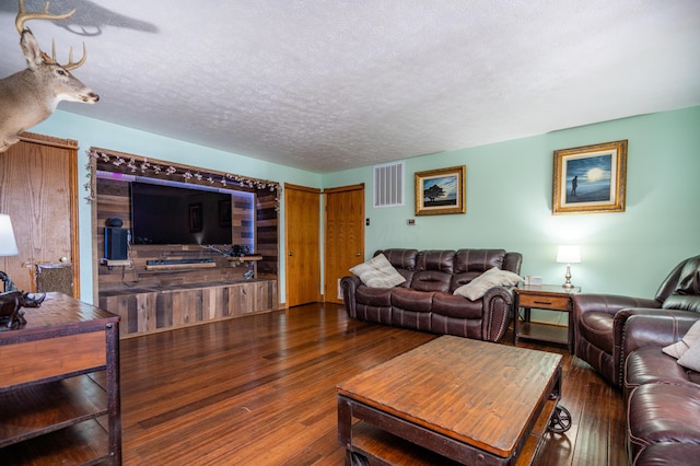 living room featuring a textured ceiling, dark wood-type flooring, and visible vents