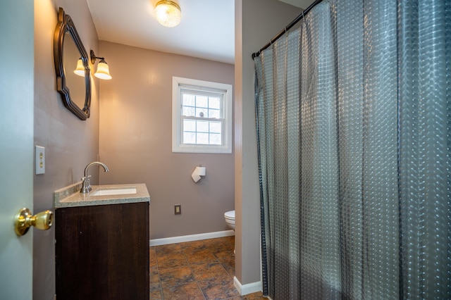 full bathroom featuring toilet, a shower with shower curtain, vanity, baseboards, and stone finish flooring