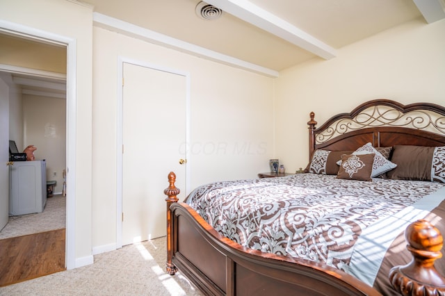 carpeted bedroom featuring visible vents, washer / clothes dryer, and beamed ceiling