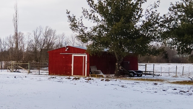 snow covered structure with an outbuilding and fence