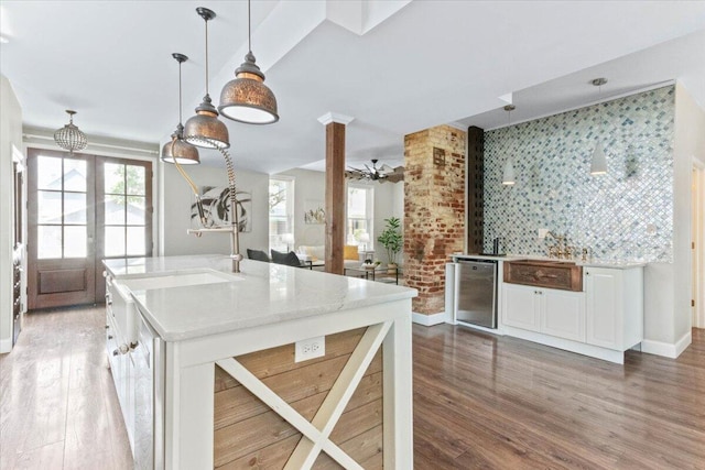 kitchen featuring hardwood / wood-style flooring, decorative light fixtures, white cabinetry, and a healthy amount of sunlight