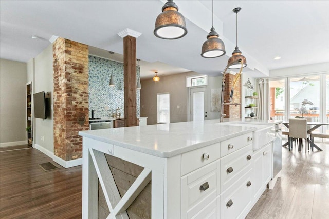 kitchen featuring white cabinetry, a center island with sink, dark hardwood / wood-style flooring, and pendant lighting