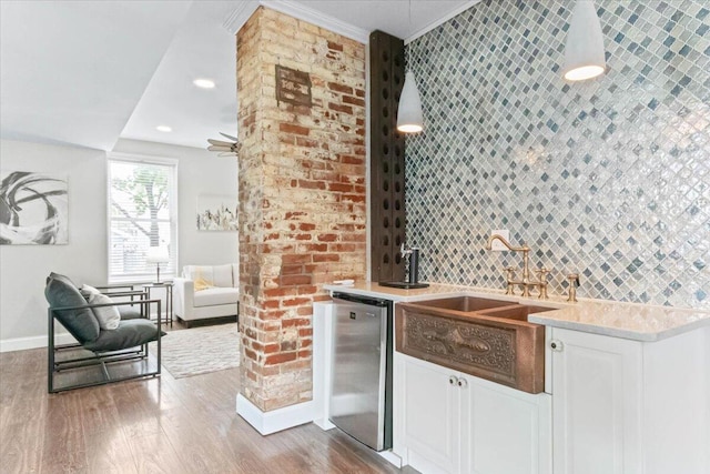 kitchen with white cabinetry, stainless steel fridge, sink, tasteful backsplash, and wood-type flooring