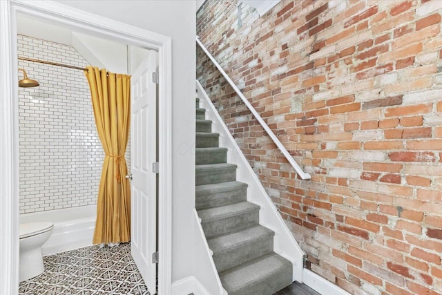 stairway with tile patterned flooring and brick wall