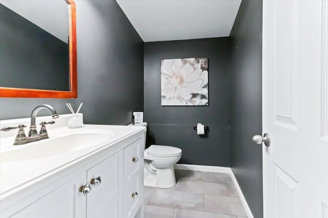 bathroom with toilet, vanity, and tile patterned flooring