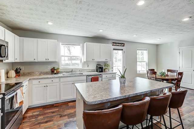 kitchen featuring appliances with stainless steel finishes, sink, white cabinetry, and a center island