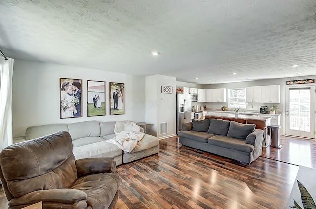 living room featuring a textured ceiling and dark hardwood / wood-style flooring