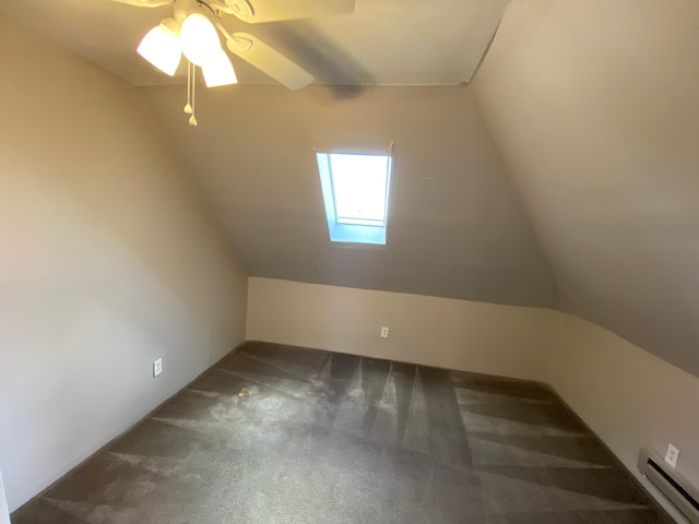 additional living space with ceiling fan, carpet flooring, a baseboard radiator, and lofted ceiling with skylight