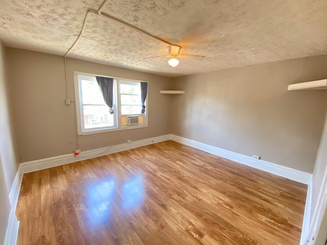 unfurnished room with hardwood / wood-style flooring, ceiling fan, cooling unit, and a textured ceiling