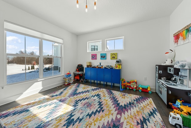 playroom featuring dark wood-type flooring and baseboards