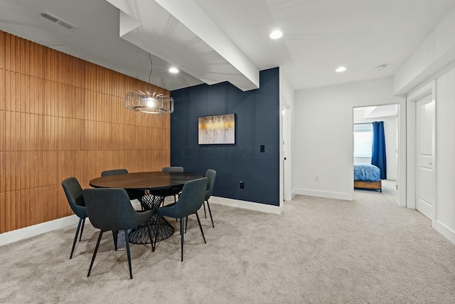 dining room featuring light carpet, recessed lighting, visible vents, and wooden walls