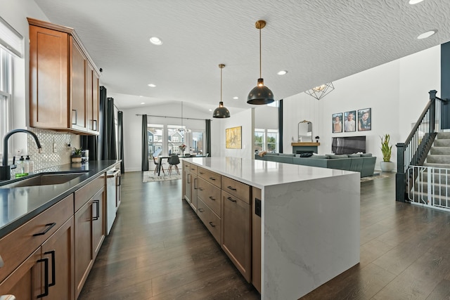 kitchen featuring dark wood-style flooring, brown cabinetry, a sink, and open floor plan