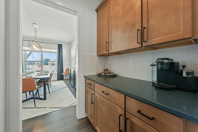 kitchen featuring dark wood-type flooring, dark countertops, brown cabinetry, and backsplash