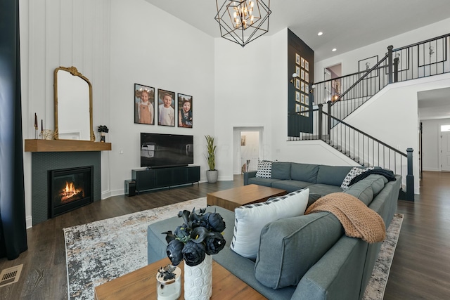 living area featuring dark wood-style floors, a fireplace, stairs, and a towering ceiling