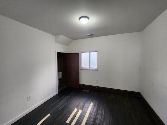 unfurnished bedroom featuring dark wood-type flooring and lofted ceiling