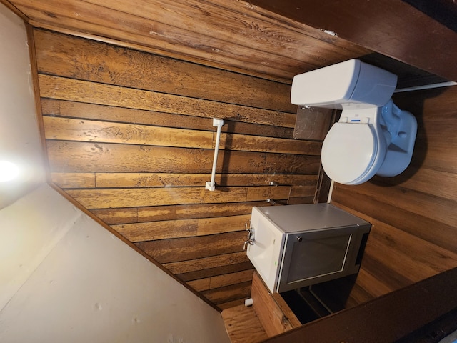 bathroom featuring wood walls and toilet