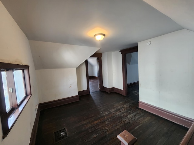 bonus room with dark wood-type flooring and vaulted ceiling