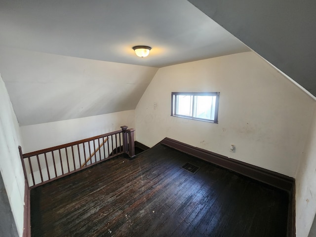 additional living space with dark wood-type flooring and vaulted ceiling