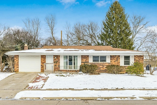 single story home with an attached garage, driveway, a chimney, and brick siding