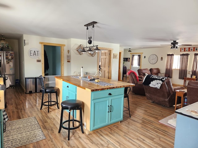 kitchen featuring a breakfast bar, wooden counters, blue cabinets, pendant lighting, and stainless steel fridge with ice dispenser