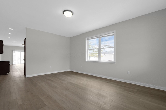 unfurnished room featuring dark wood-type flooring, recessed lighting, baseboards, and a barn door