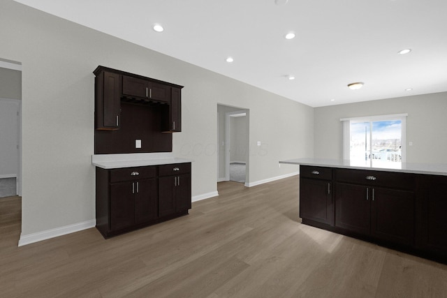 kitchen with baseboards, light wood-style flooring, light countertops, dark brown cabinets, and recessed lighting