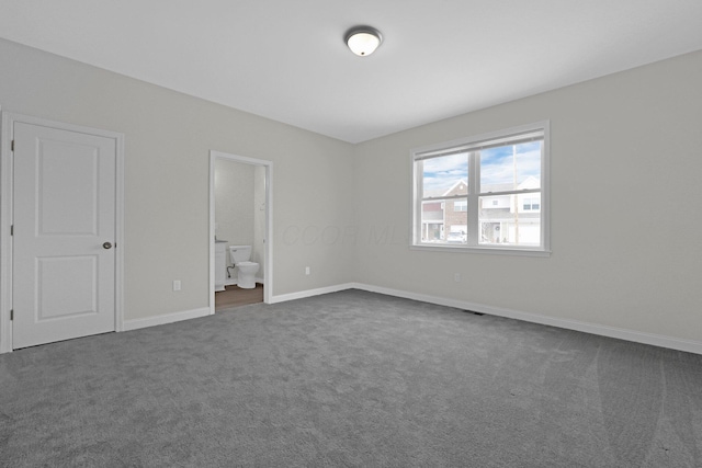 unfurnished bedroom with ensuite bath, visible vents, baseboards, and dark colored carpet