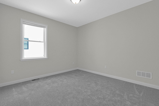 carpeted empty room featuring visible vents and baseboards