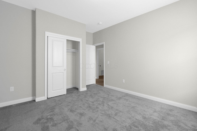 unfurnished bedroom with dark colored carpet, a closet, and baseboards