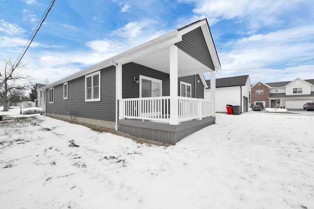 snow covered property featuring a garage and covered porch