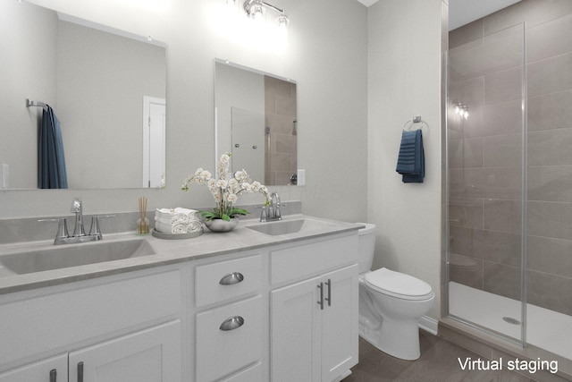 full bath with double vanity, tiled shower, a sink, and toilet