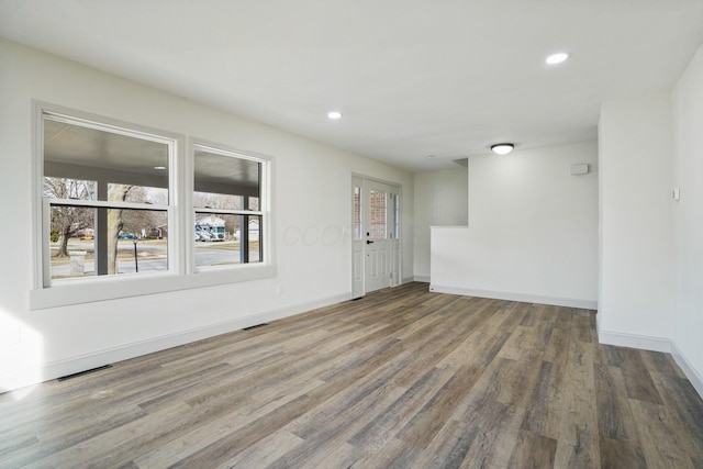 unfurnished room featuring recessed lighting, wood finished floors, visible vents, and baseboards