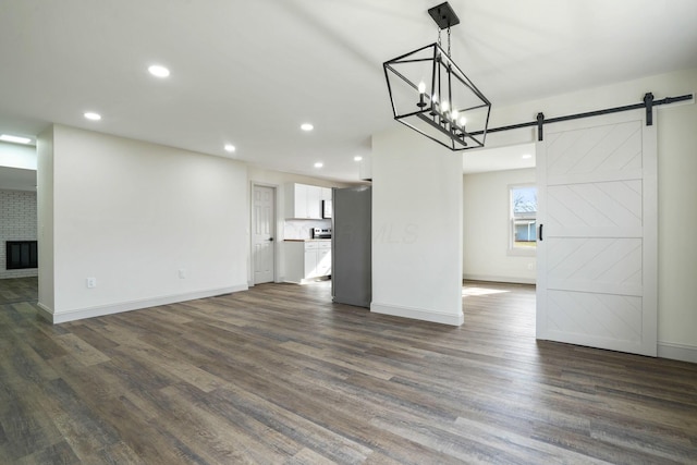 unfurnished living room featuring recessed lighting, a fireplace, dark wood finished floors, and a barn door