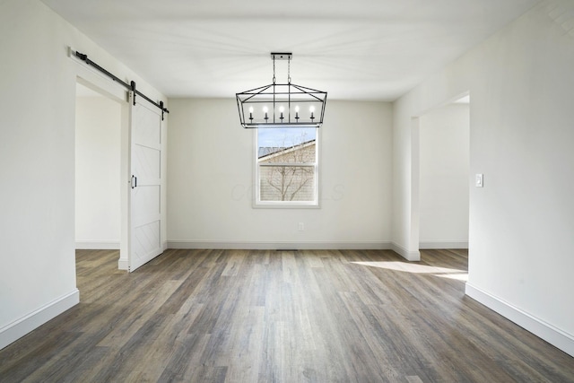 unfurnished dining area featuring a barn door, baseboards, and dark wood-type flooring