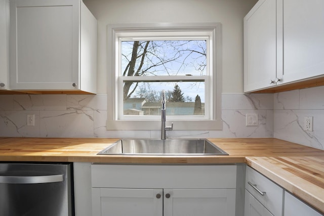 kitchen featuring wooden counters, a sink, and white cabinets