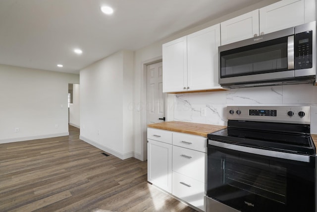 kitchen with wooden counters, appliances with stainless steel finishes, white cabinetry, and tasteful backsplash