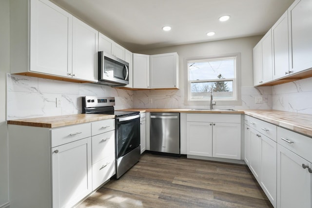 kitchen featuring recessed lighting, dark wood-style flooring, white cabinets, appliances with stainless steel finishes, and decorative backsplash