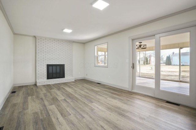 unfurnished living room featuring light wood-type flooring, a fireplace, visible vents, and crown molding