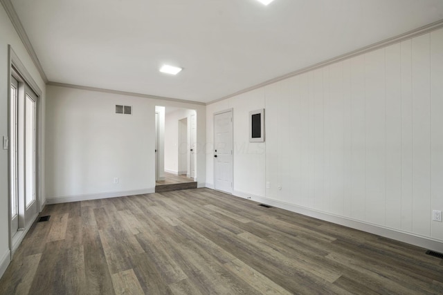 empty room featuring visible vents, ornamental molding, dark wood finished floors, and baseboards