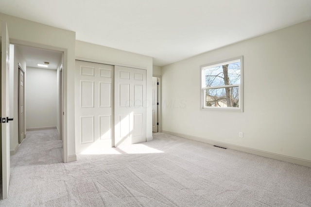 unfurnished bedroom featuring light carpet, baseboards, and a closet