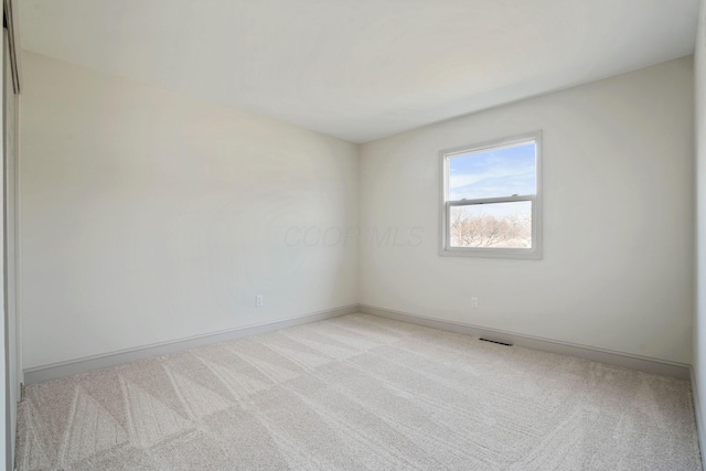 unfurnished room with baseboards, visible vents, and light colored carpet