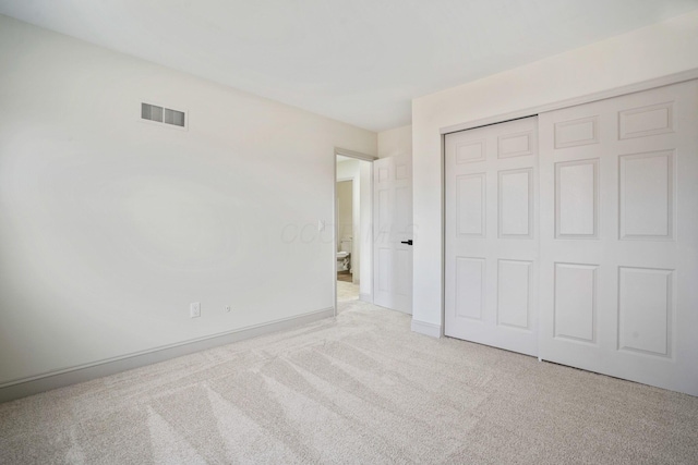 unfurnished bedroom featuring light carpet, baseboards, visible vents, and a closet