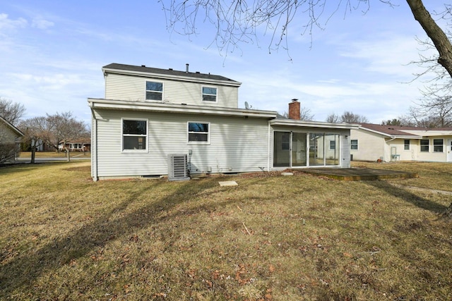 rear view of property featuring central air condition unit, a chimney, a lawn, and a patio