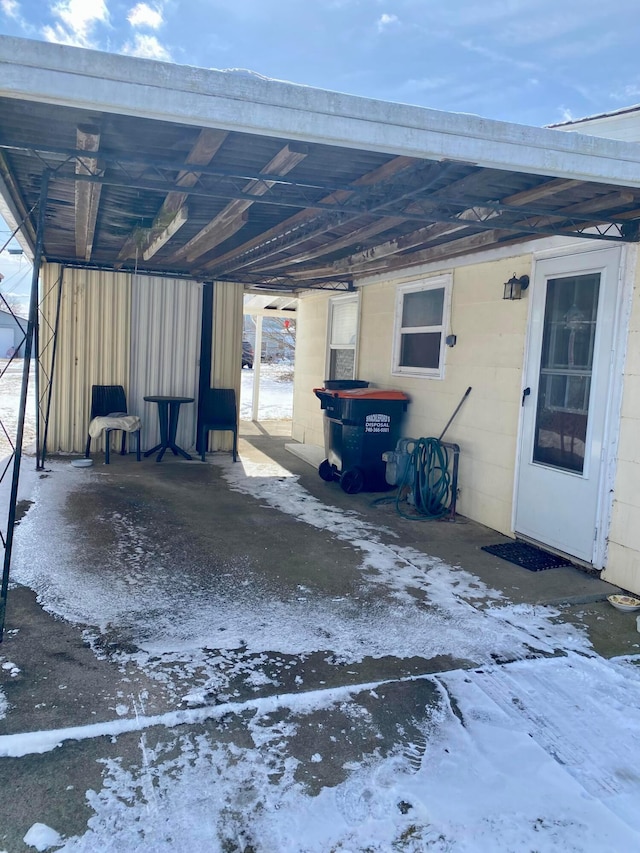 snow covered parking area with a carport