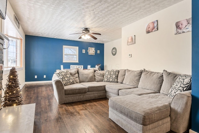 living room with a textured ceiling, dark wood-type flooring, and ceiling fan